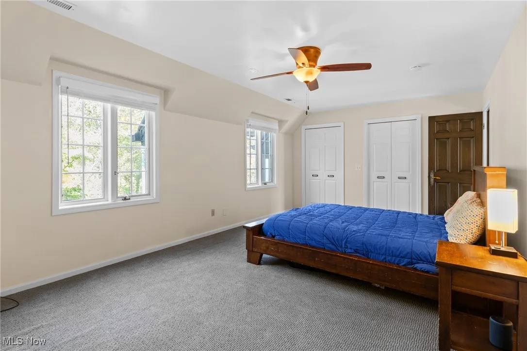 Carpeted bedroom with two closets and a ceiling fan