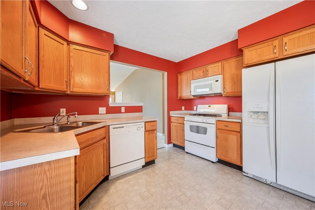 Kitchen with white appliances, light countertops, an ample cabinetry facing living room