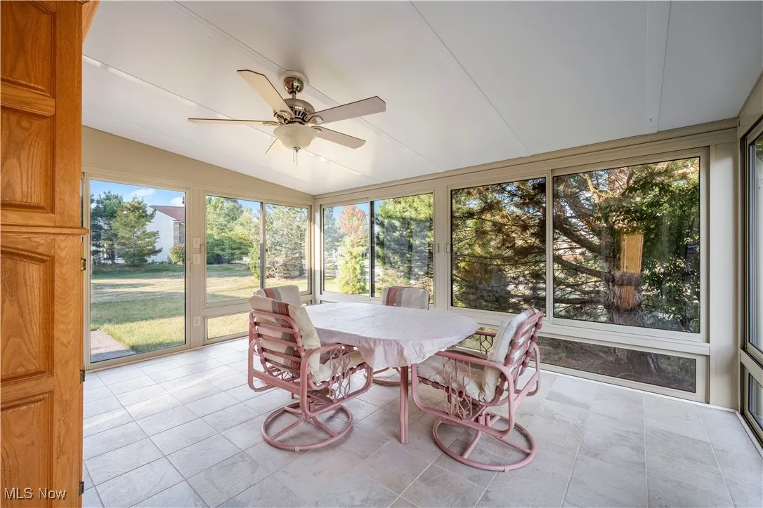 Sunroom / solarium featuring outdoor dining space, ceiling fan, and lofted ceiling surrounding by glass sliders