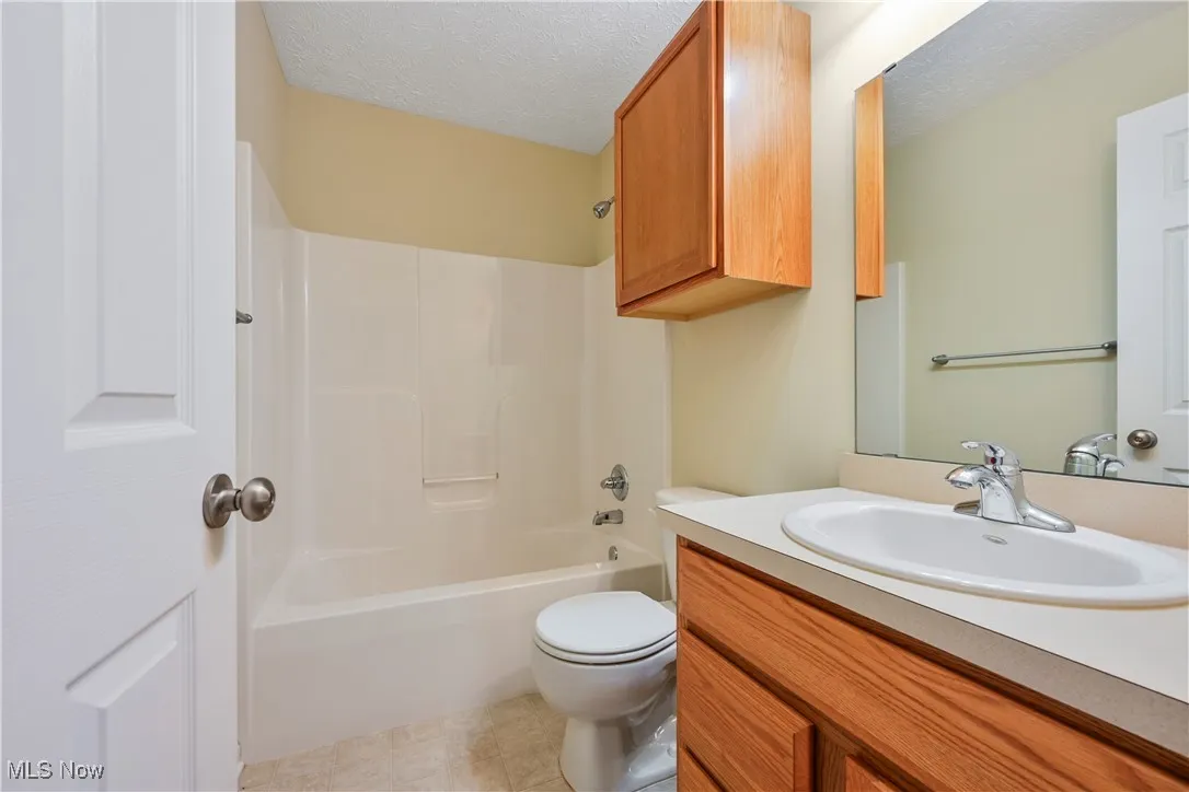Bathroom with shower / tub combination, vanity, and a textured ceiling