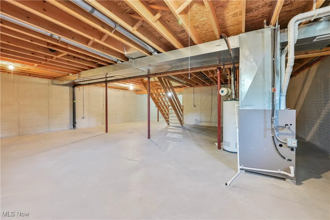 Unfinished below grade area with water heater, stairs, and heating unit
