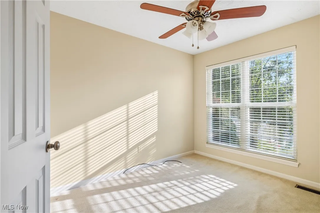 Carpeted den/office in front of home with baseboards and ceiling fan