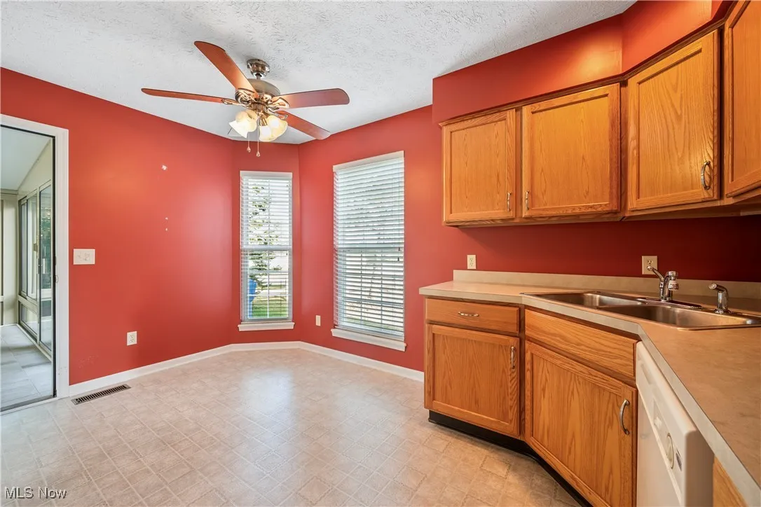 Kitchen with light countertops, a textured ceiling, white dishwasher, ceiling fan, with room for dining table