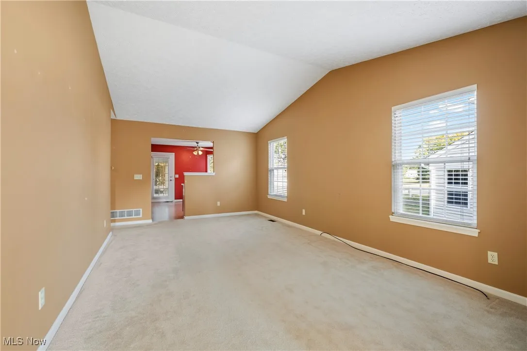 Living room open to kitchen with two natural light providing windows