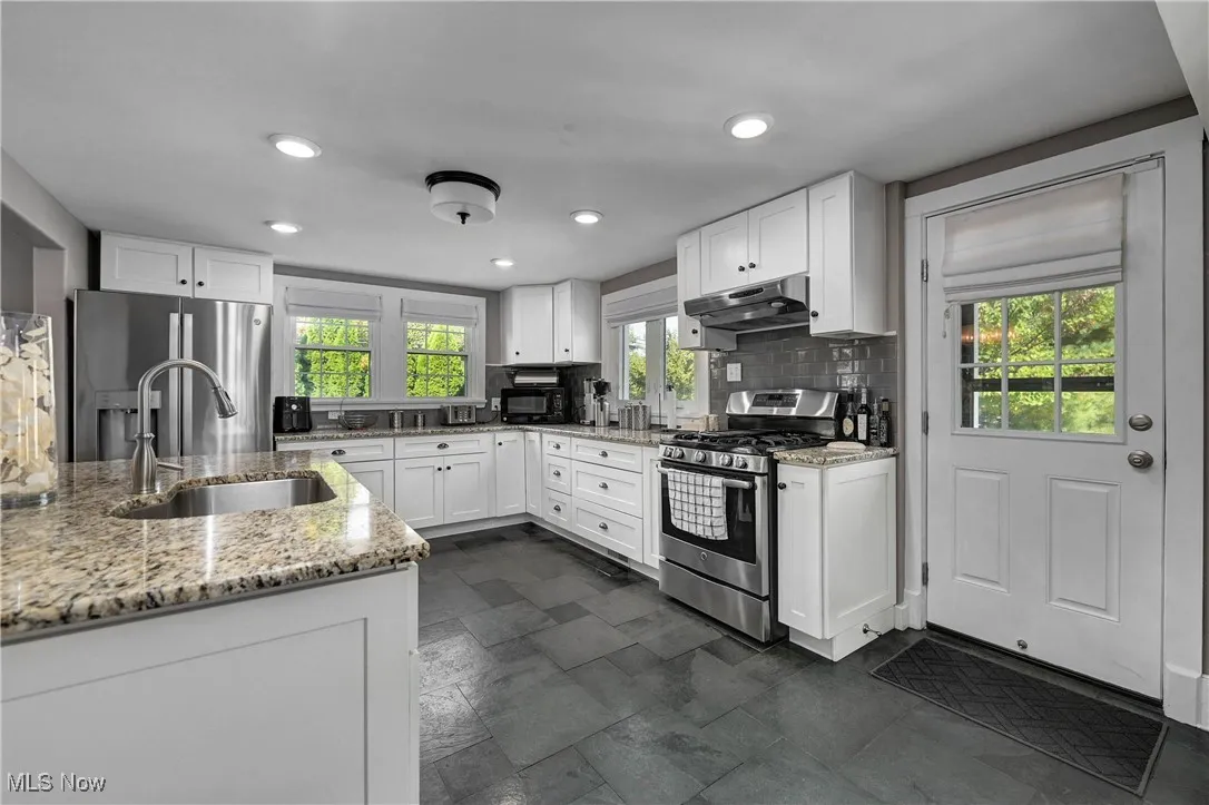 Kitchen featuring white cabinets, appliances with stainless steel finishes, light stone counters, recessed lighting, and under cabinet range hood