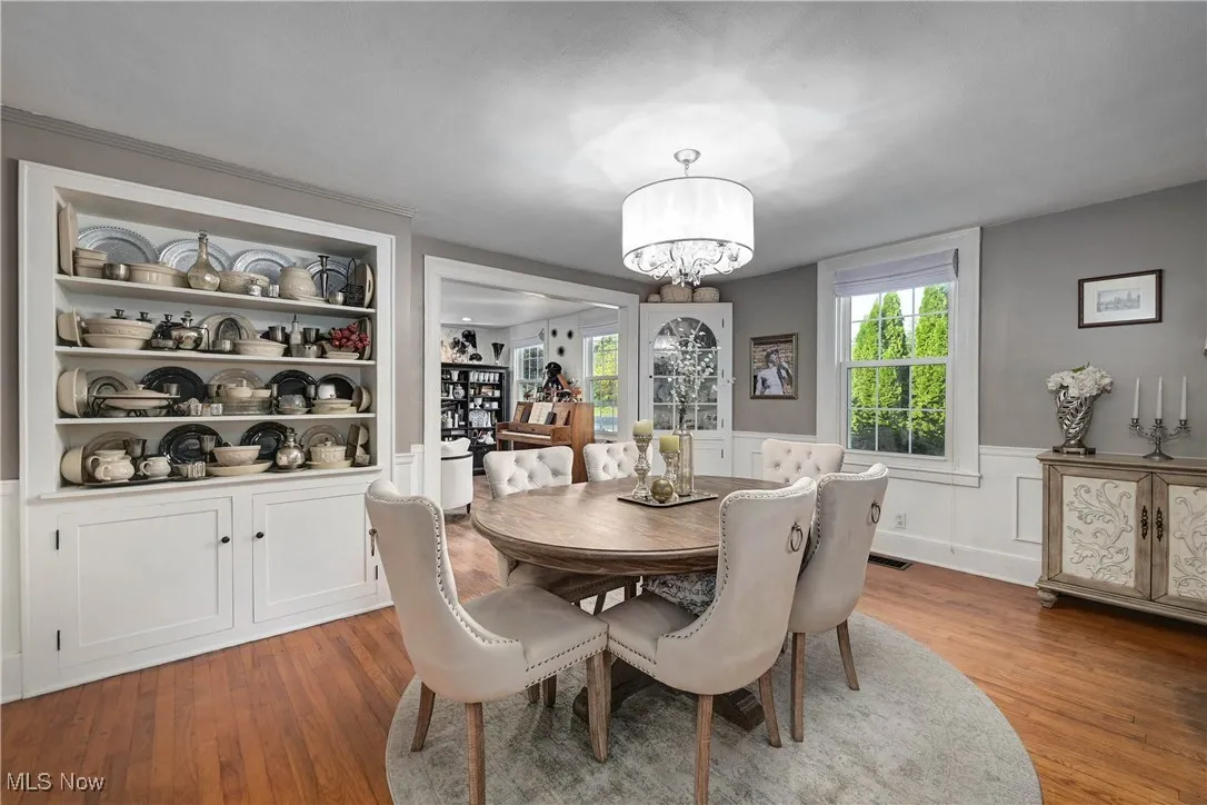 Dining room featuring plenty of natural light, a wainscoted wall, light wood-style floors, a chandelier, and a decorative wall