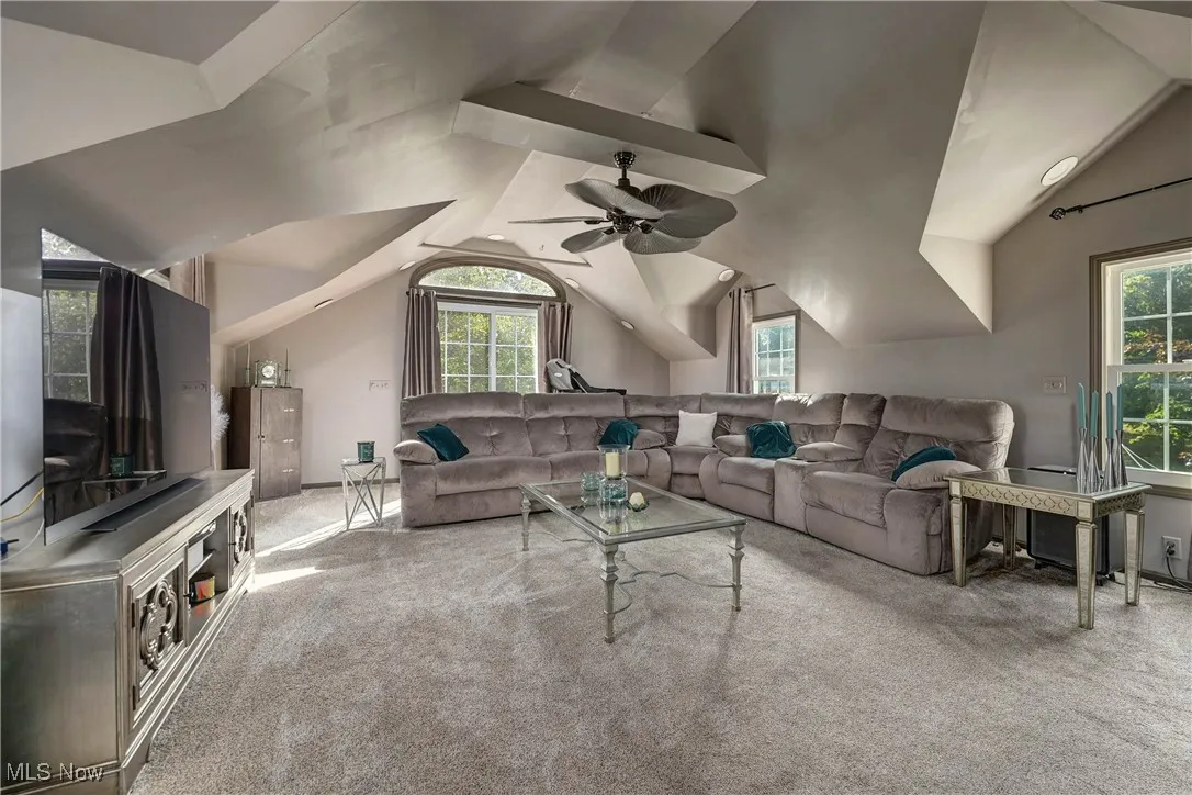 Carpeted living room featuring vaulted ceiling and ceiling fan