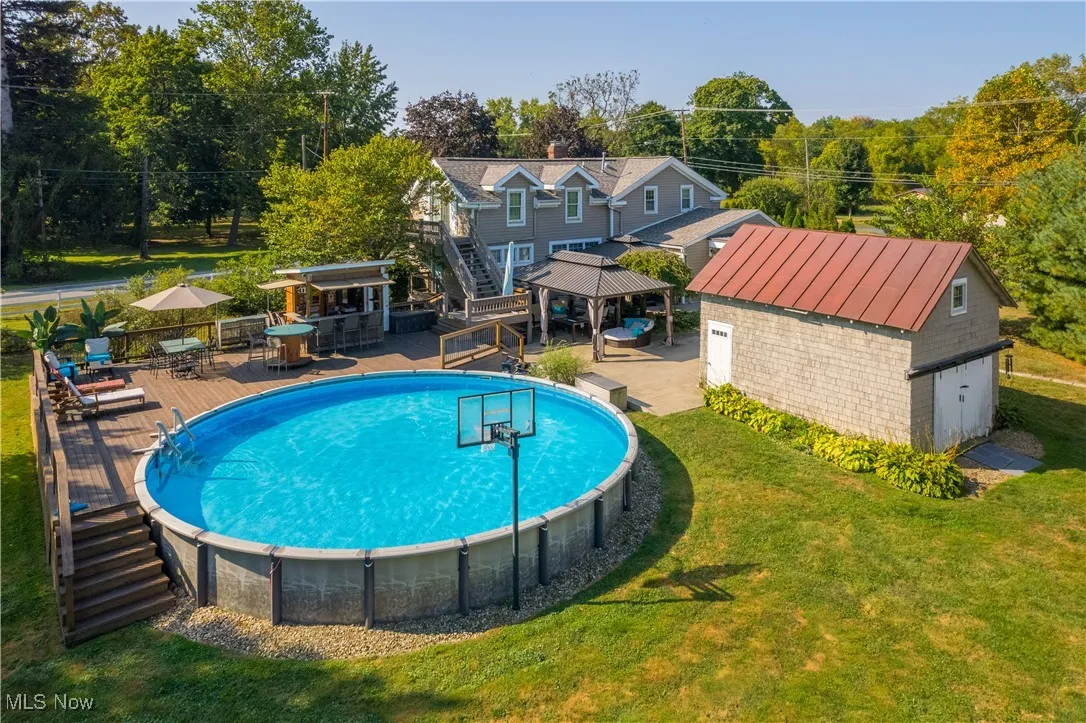 View of swimming pool featuring an outbuilding, a patio, stairway, a yard, and a deck