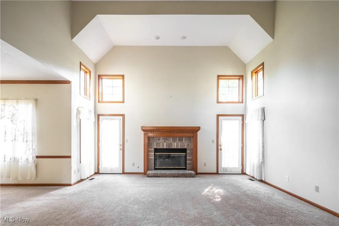 Spacious living room with high ceilings, windows and a fireplace