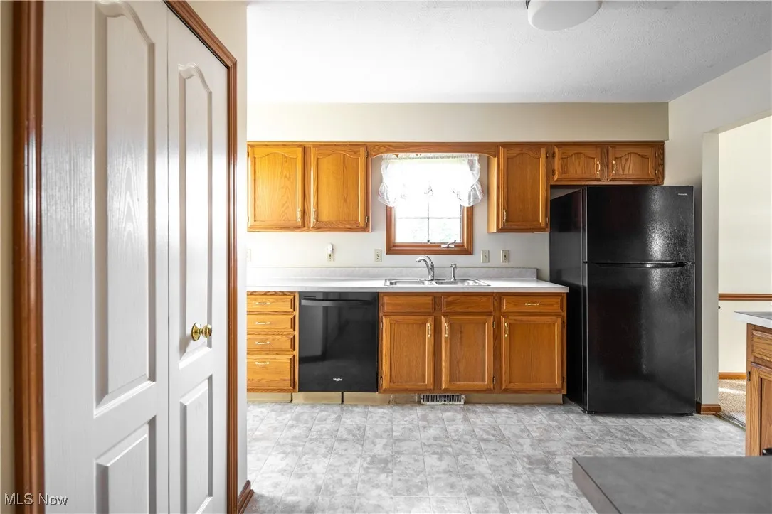 Kitchen with black appliances, light countertops, and brown cabinets