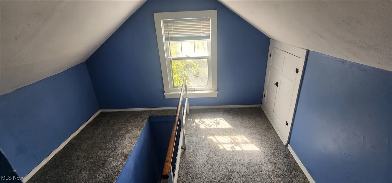 Additional living space with carpet flooring, vaulted ceiling, and a textured ceiling