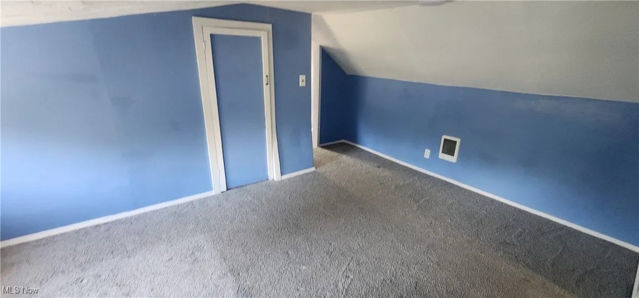 Additional living space with vaulted ceiling and carpet flooring