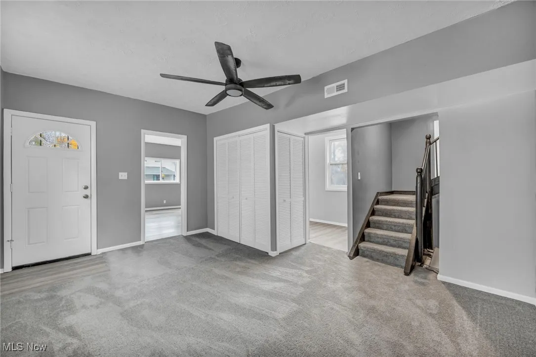 Foyer with light colored carpet, stairs, ceiling fan, and a textured ceiling