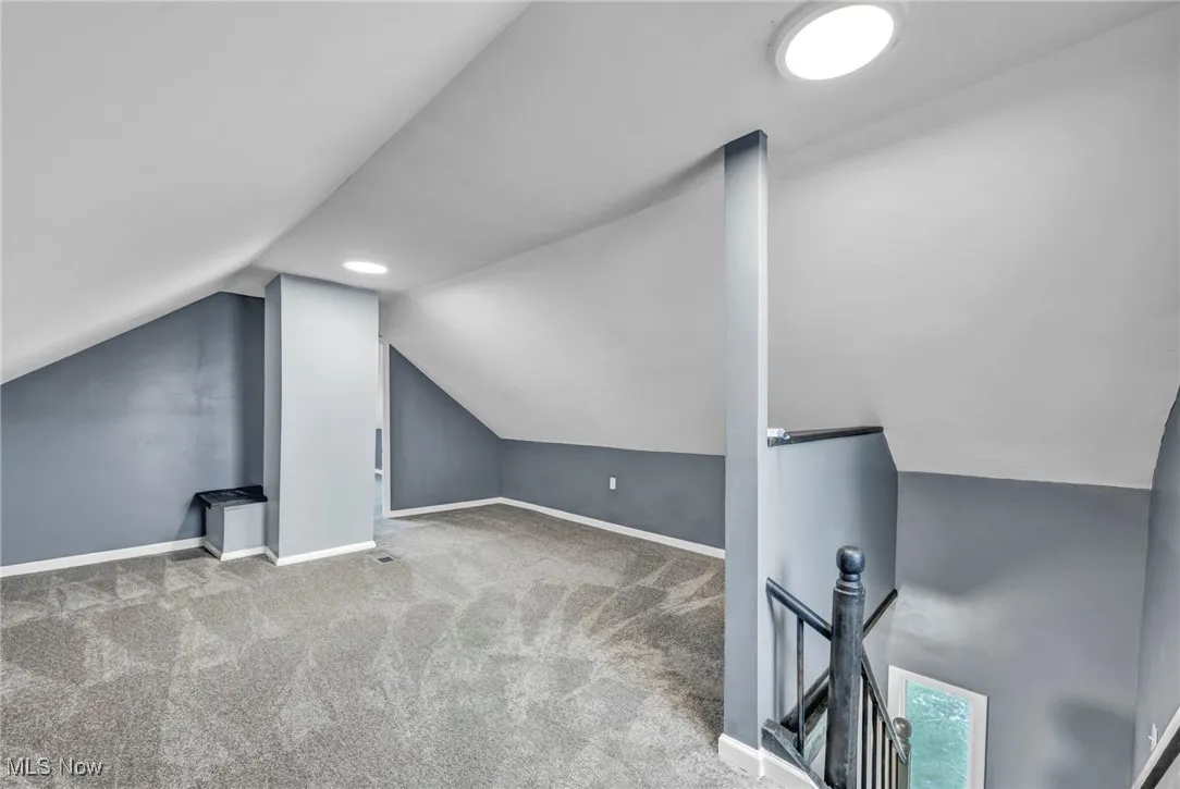Bonus room with lofted ceiling and carpet