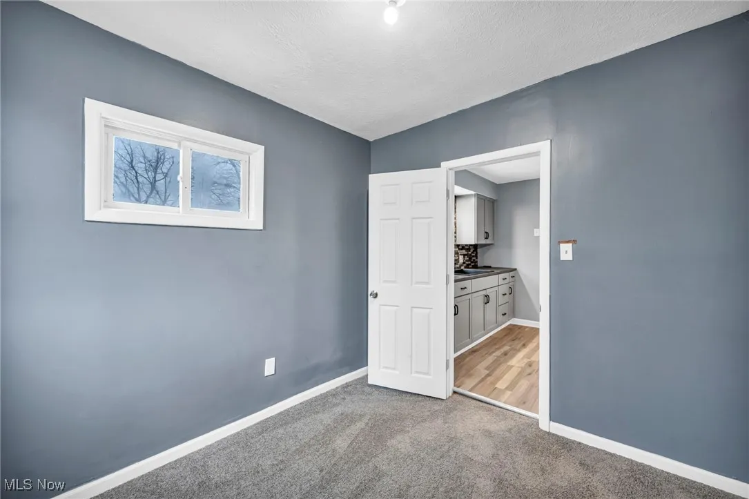 Unfurnished bedroom featuring dark carpet, a textured ceiling, and connected bathroom