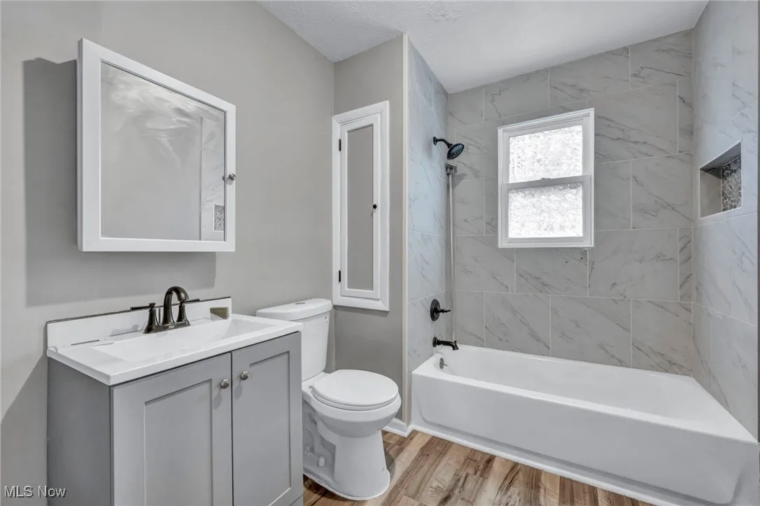 Full bath with shower / bathtub combination, vanity, light wood-style flooring, and a textured ceiling