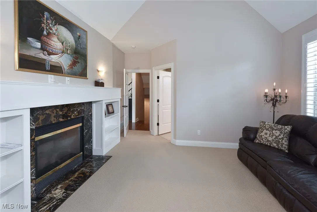 Living room with a fireplace, carpet flooring, and lofted ceiling