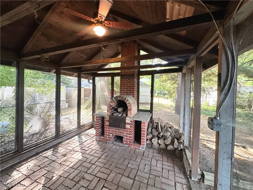 Sunroom / solarium with a fireplace, a ceiling fan, plenty of natural light, and a patio