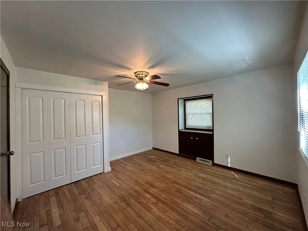Unfurnished bedroom with a closet, dark wood finished floors, and a ceiling fan