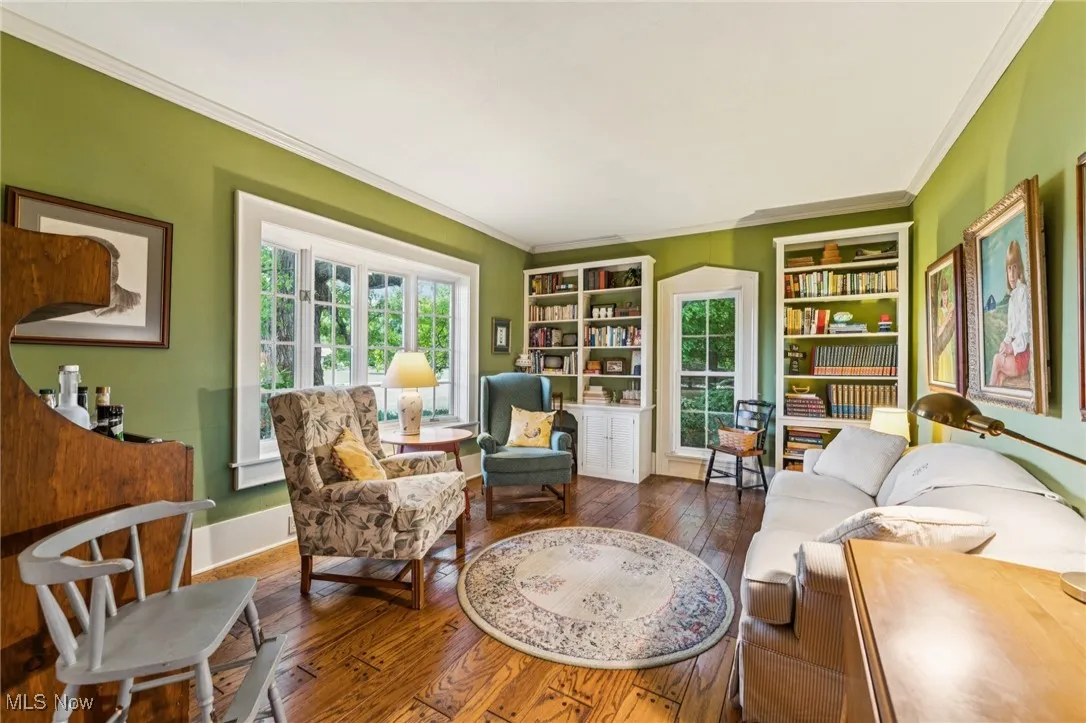 Living area with hardwood / wood-style floors, healthy amount of natural light, and ornamental molding