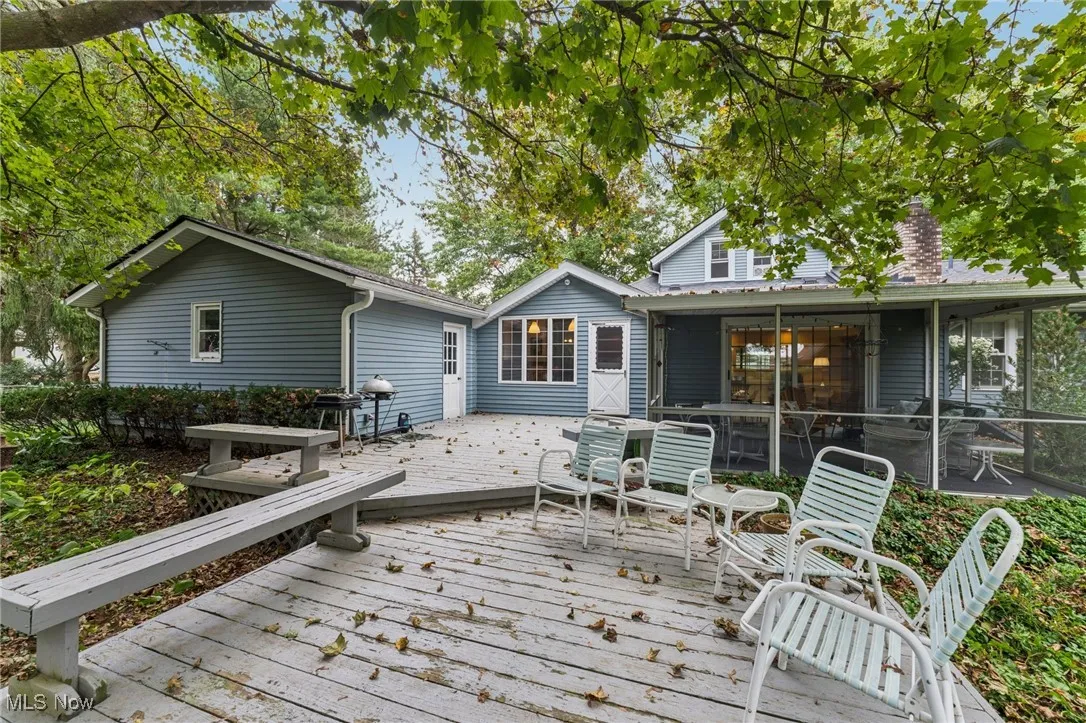 Rear view of house with a deck, a chimney, and a sunroom