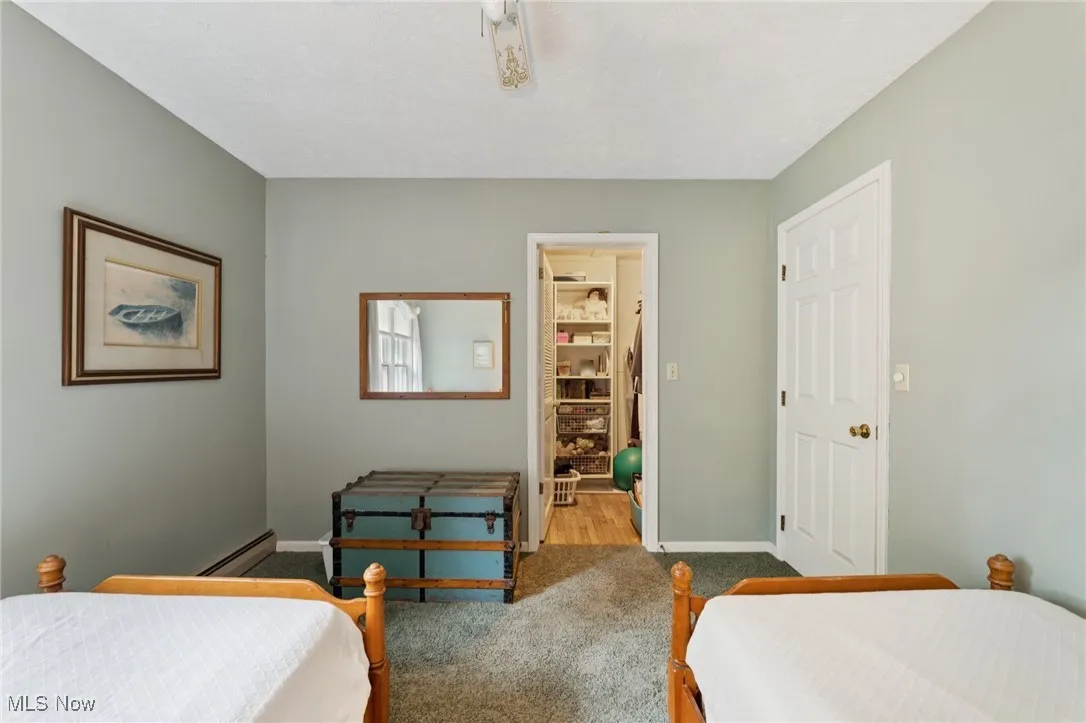 Carpeted bedroom with a baseboard heating unit and baseboards