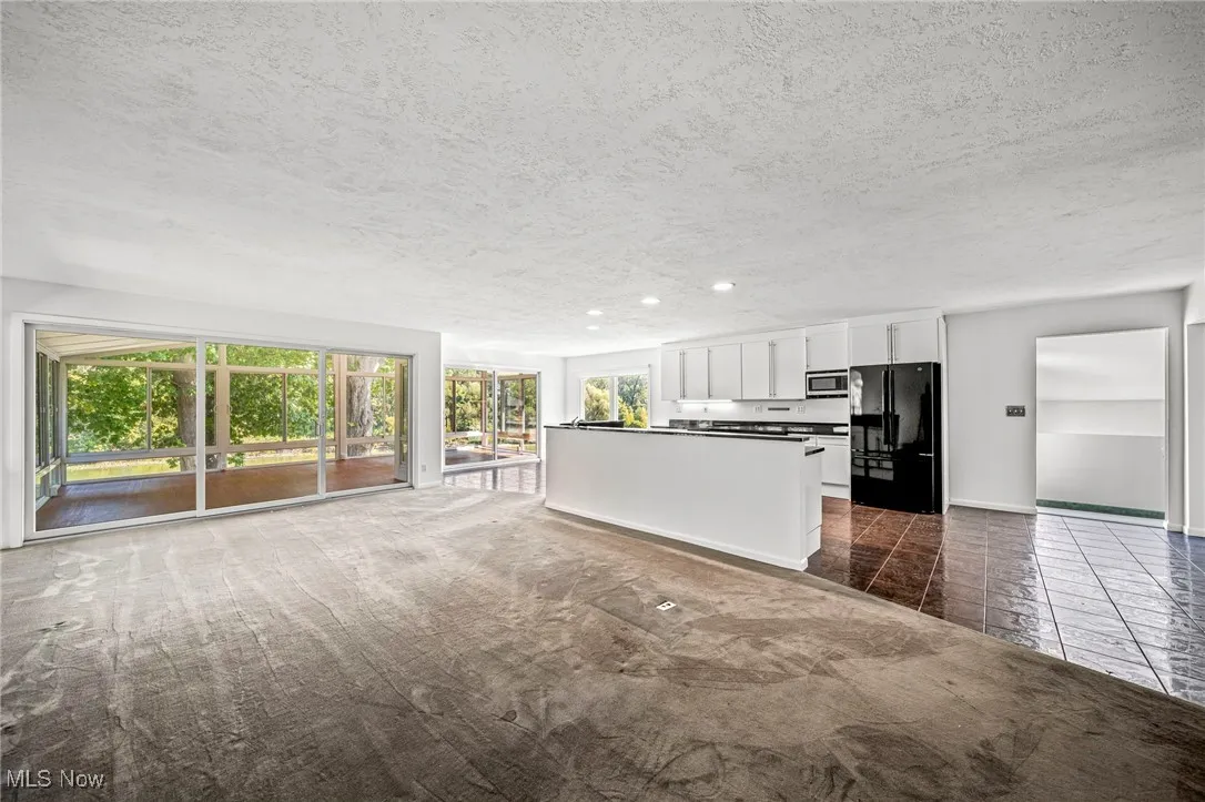 Unfurnished living room featuring a textured ceiling, recessed lighting, dark tile patterned flooring, and dark colored carpet