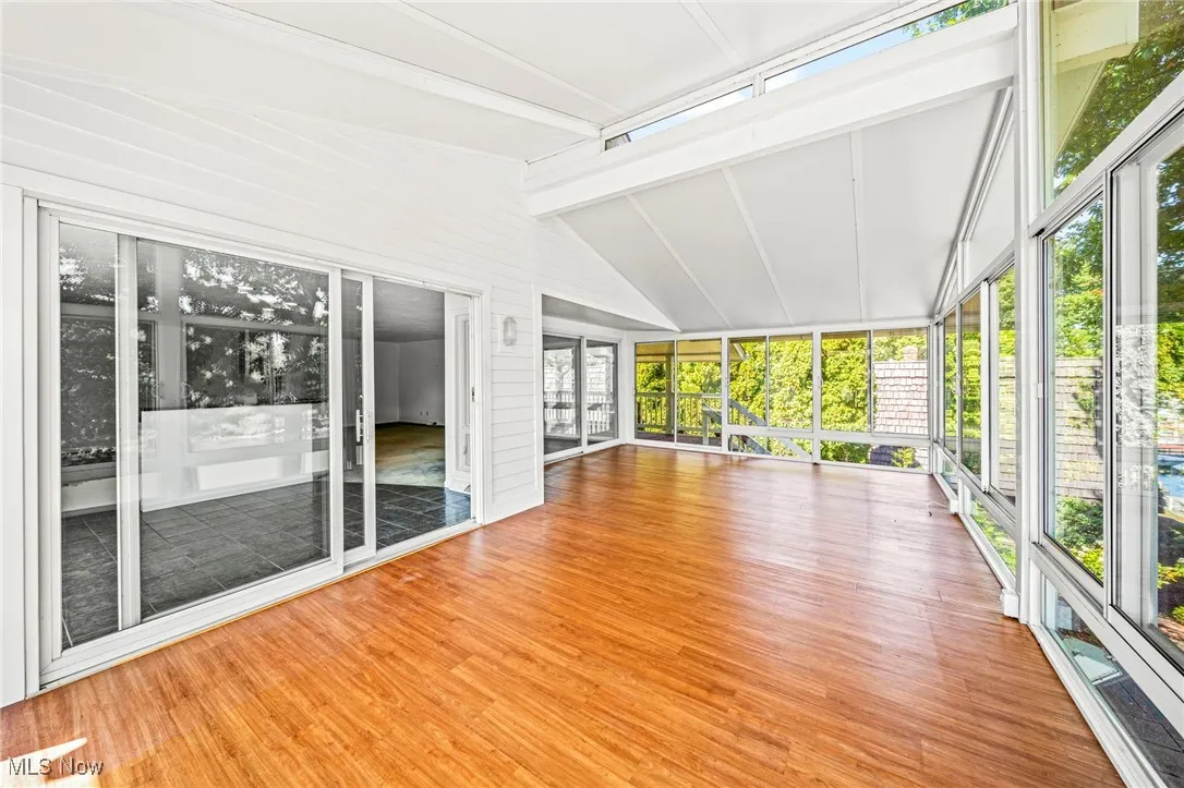 sunroom featuring wood finished floors, expansive windows, and wood walls