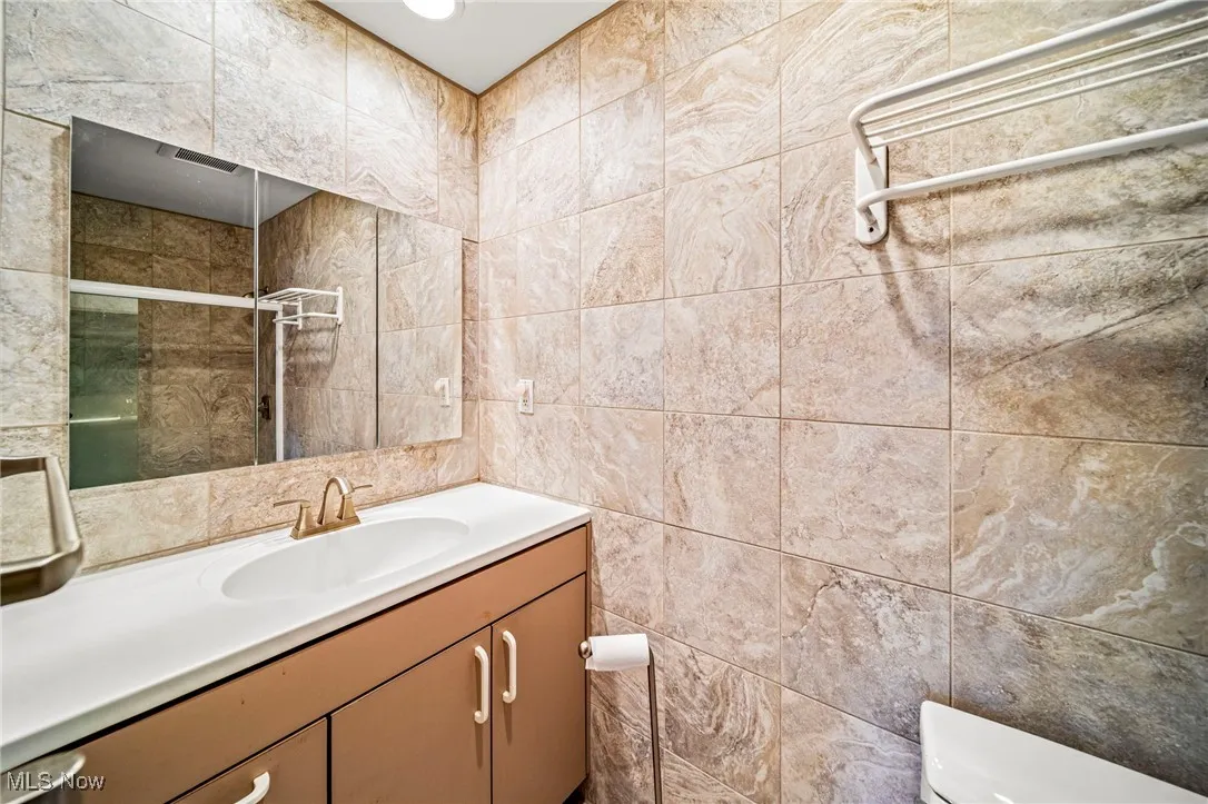 Bathroom with vanity, tile walls, and a shower stall