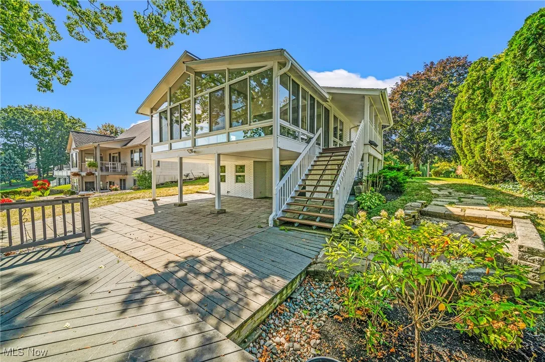 Back of property featuring a wooden deck, stairs, a patio area, and a sunroom