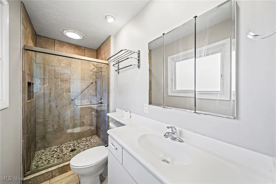 Bathroom with vanity, a stall shower, light tile patterned flooring, and a textured ceiling