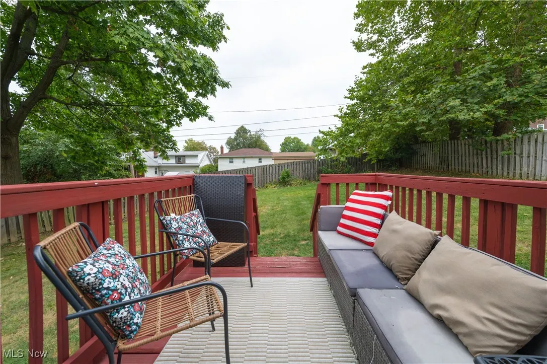 Wooden terrace with an outdoor living space and a fenced backyard