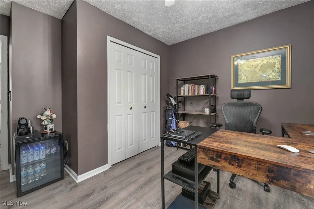 Office area with a textured ceiling and light wood-type flooring