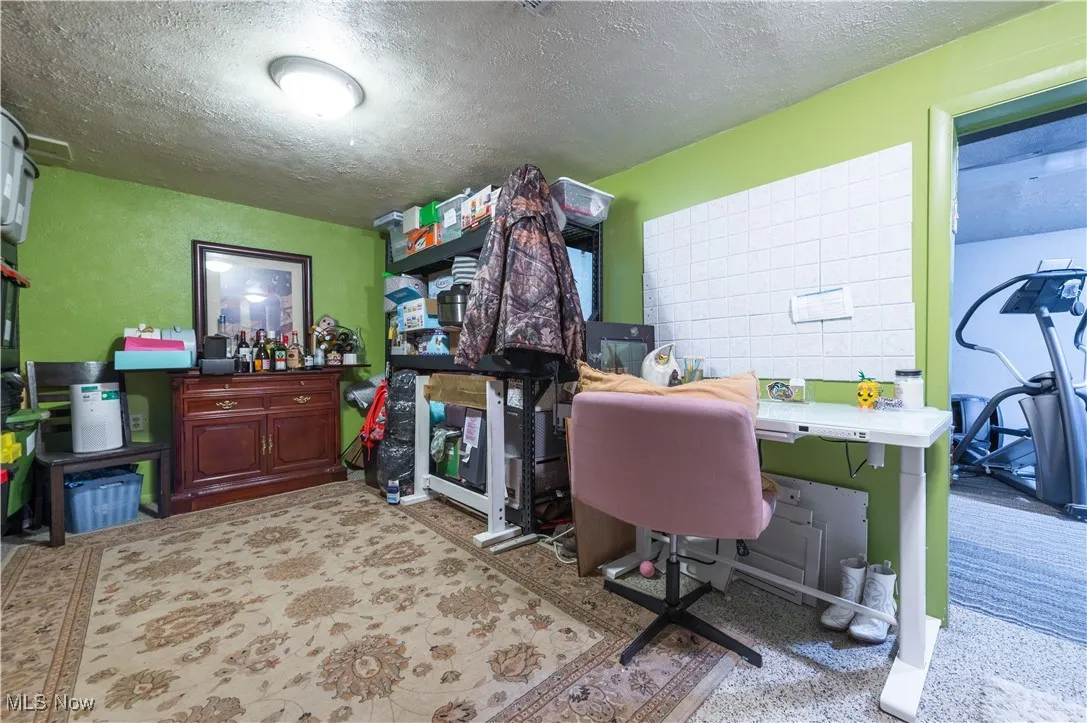 Office space with a textured ceiling and light colored carpet
