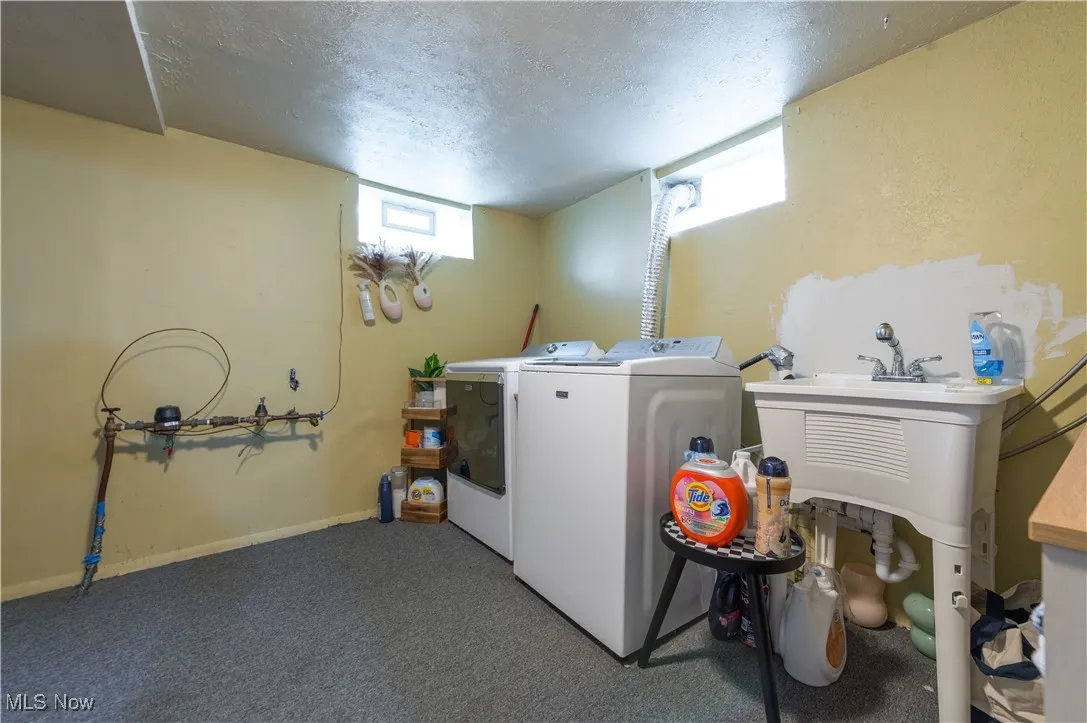 Laundry area with a textured ceiling, dark carpet, and washing machine and dryer