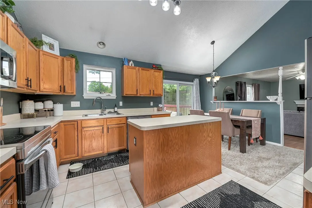 Kitchen with brown cabinets, light countertops, decorative light fixtures, vaulted ceiling, and a textured ceiling