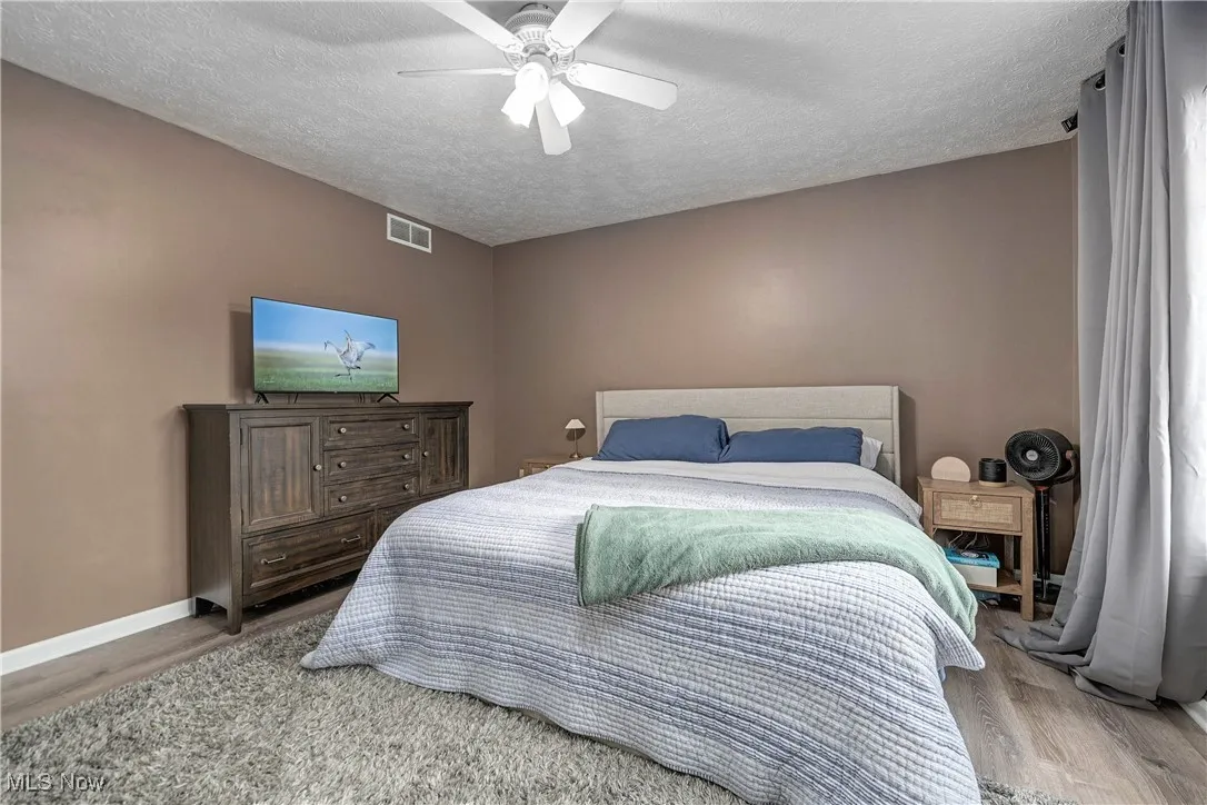 Bedroom with wood finished floors, a textured ceiling, and a ceiling fan