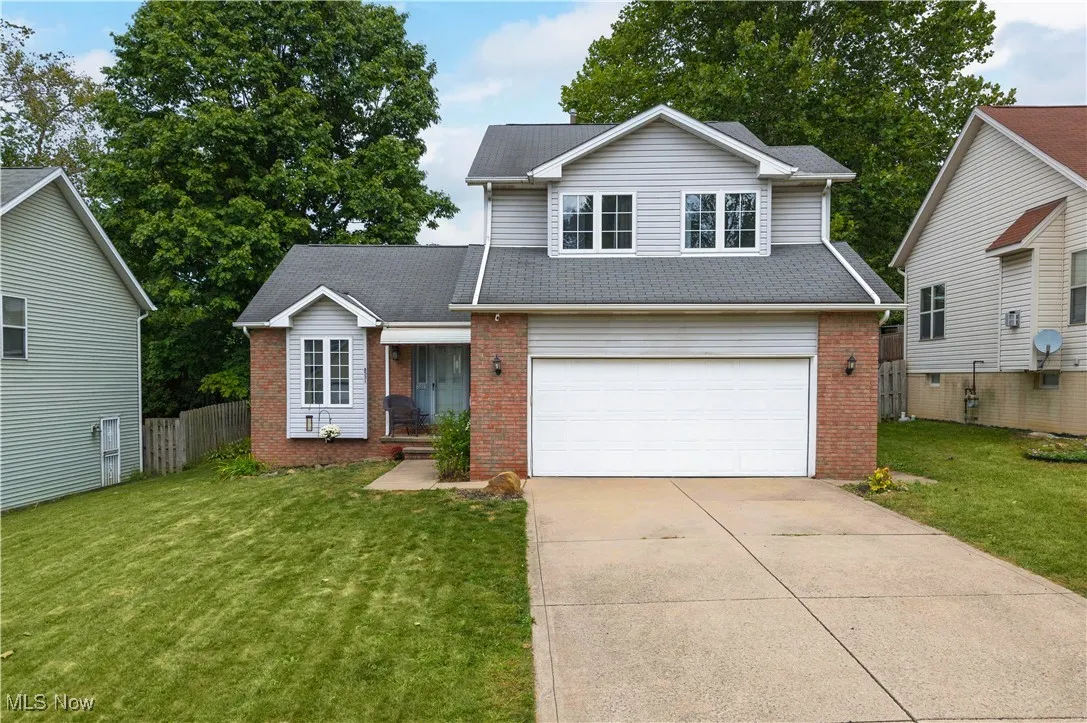 Traditional home with brick siding, concrete driveway, a garage, and roof with shingles