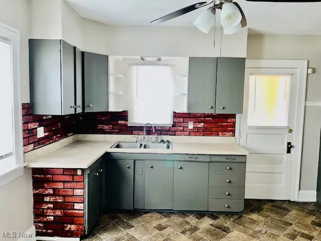 Kitchen featuring open shelves, l countertops,and a ceiling fan