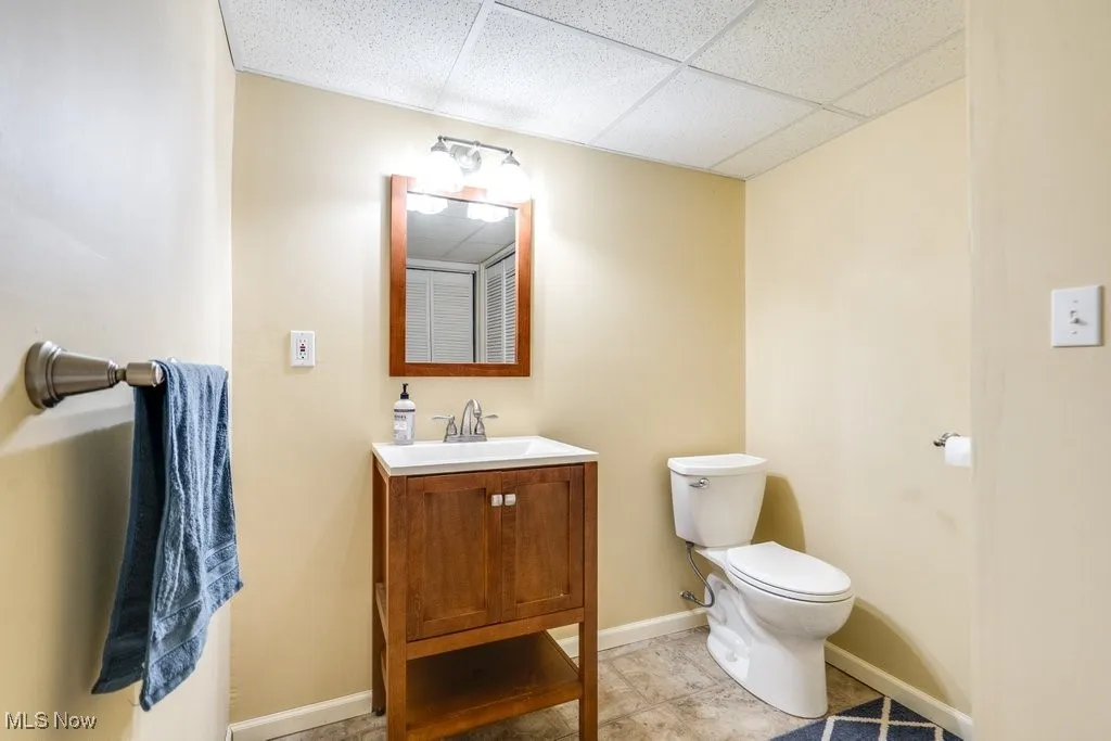 Half bath with vanity, a drop ceiling, and light tile patterned floors