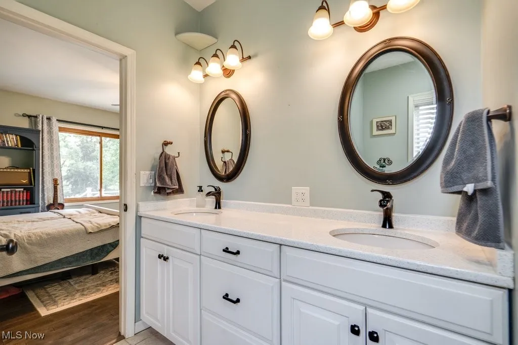 Ensuite bathroom with double vanity and light wood-style floors