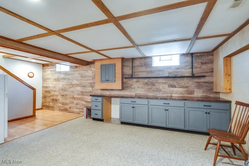 Kitchen with plenty of natural light, gray cabinetry, open shelves, and wood walls