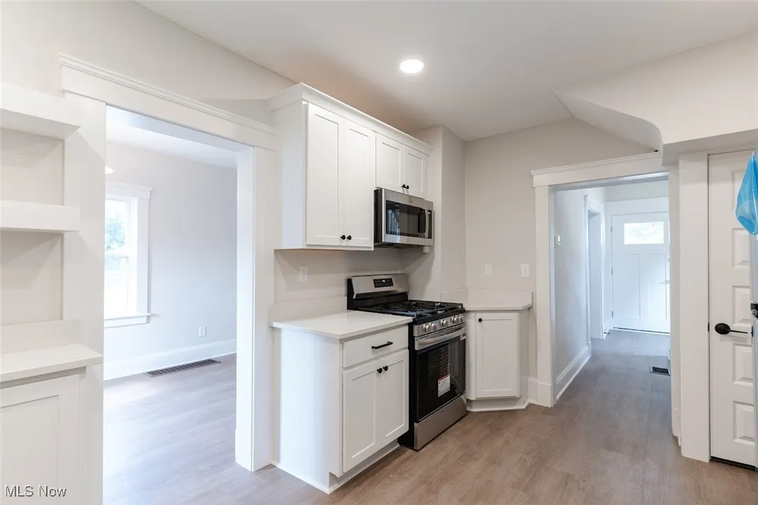 Kitchen featuring stainless steel appliances, white cabinetry, light wood-type flooring, open shelves, and recessed lighting