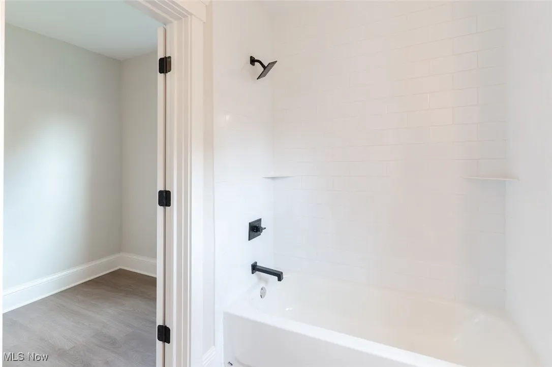 Bathroom with bathing tub / shower combination and light wood-style floors