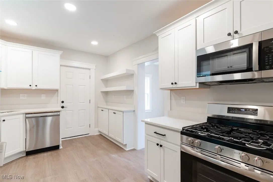 Kitchen featuring appliances with stainless steel finishes, white cabinets, open shelves, light wood-style flooring, and recessed lighting
