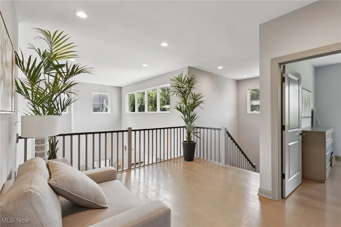 Sitting room with recessed lighting, plenty of natural light, an upstairs landing, and light wood-type flooring