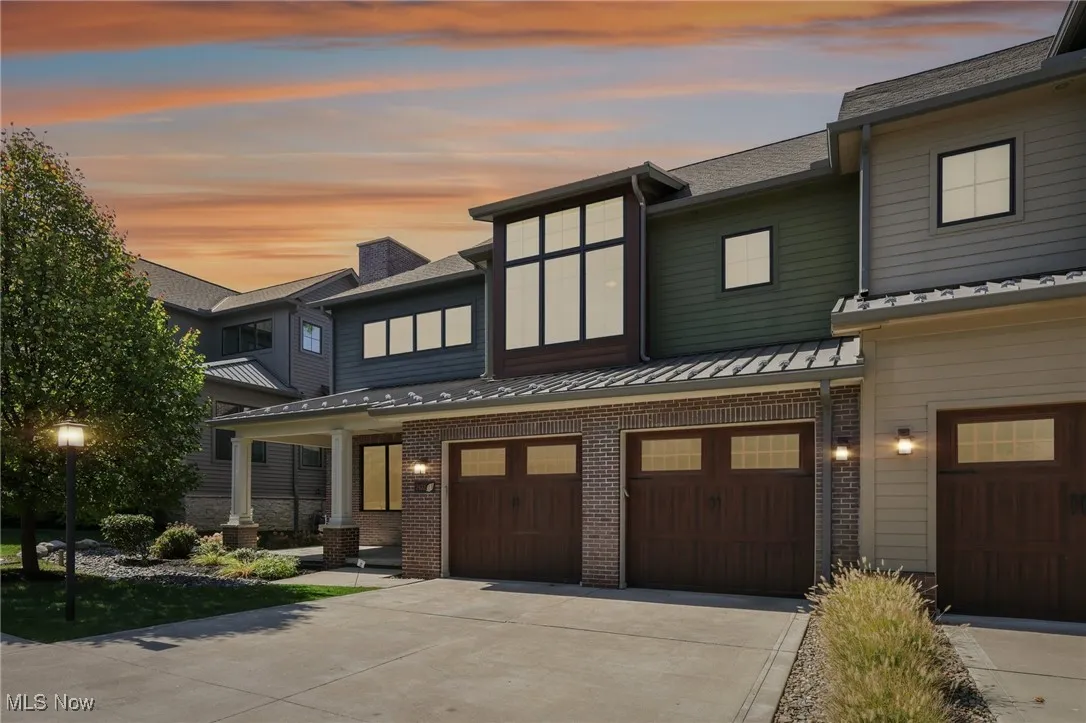 View of front of property with brick siding, concrete driveway, a garage, and a porch