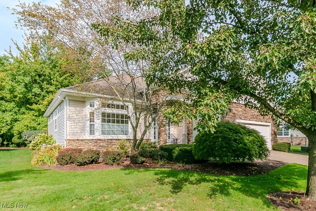 View of front of house with stone siding, a front lawn, and a garage
