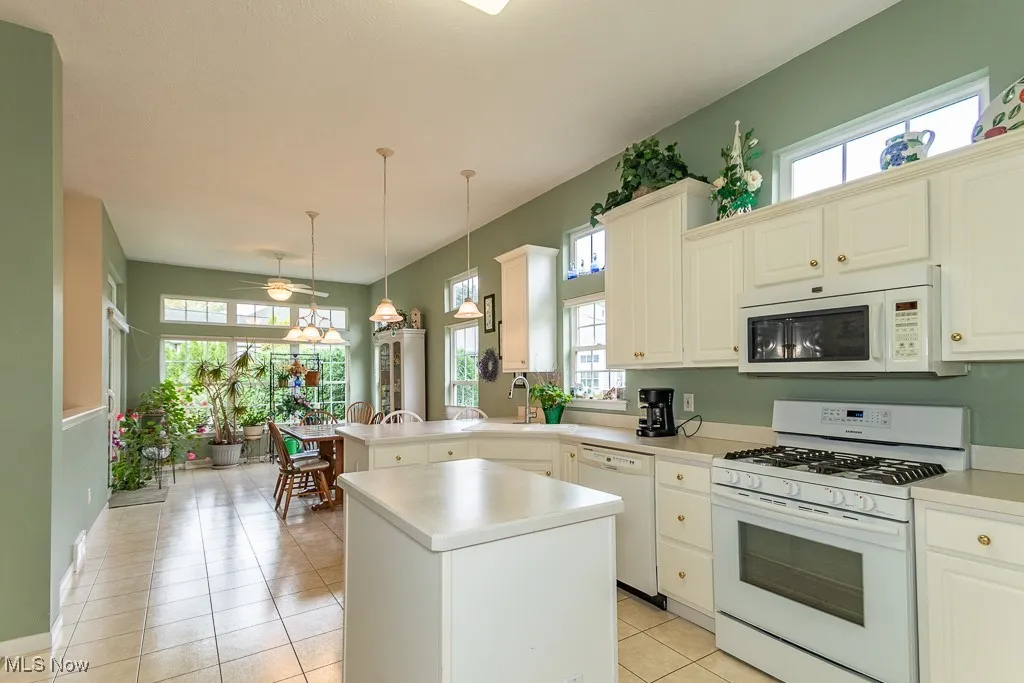Kitchen with white appliances, healthy amount of natural light, light countertops, and hanging light fixtures