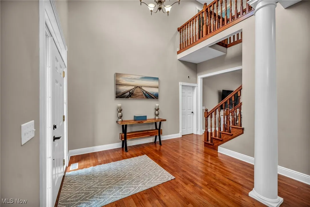 Entryway with decorative columns, a high ceiling, stairway, wood finished floors, and a chandelier